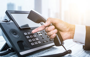 A man in a suit holding the telephone while dialing out.